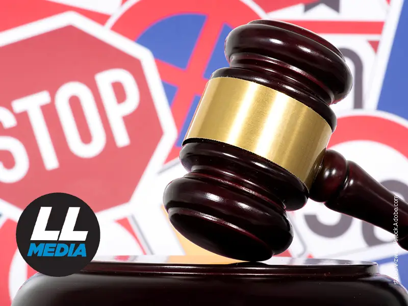 Judicial gavel in the foreground with red stop signs in the background, symbolizing legal enforcement or a ruling.