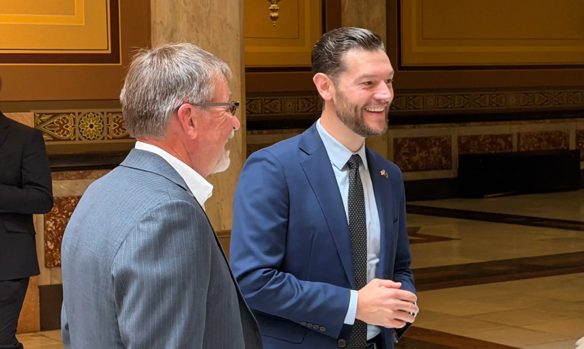 Two men in suits talk inside the Indiana Statehouse (photo: Indiana Capital Chronicle)